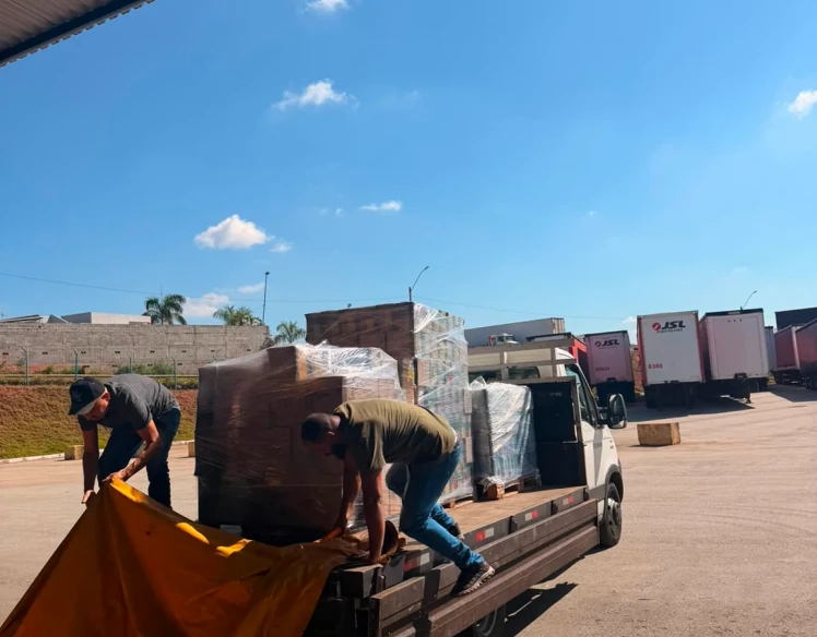 Equipe da MFS cobrindo carga paletizada com lona antes do transporte